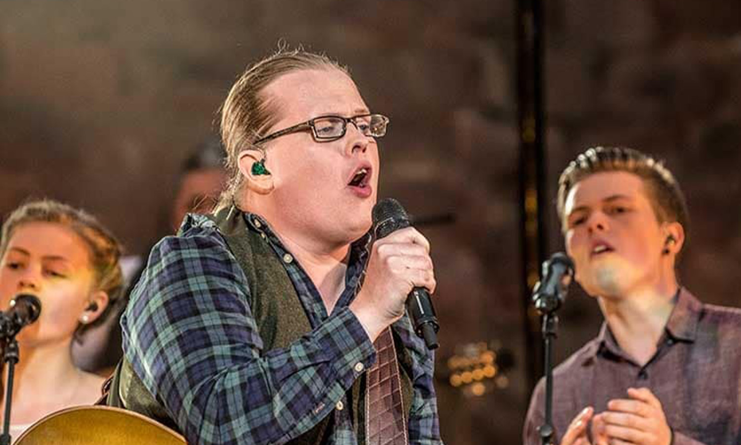 Angelo Kelly steht mit seiner Familie und Instrumenten auf der beleuchteten Open-Air-Bühne der Burgruine beim Neuleininger Burgsommer vor Publikum.