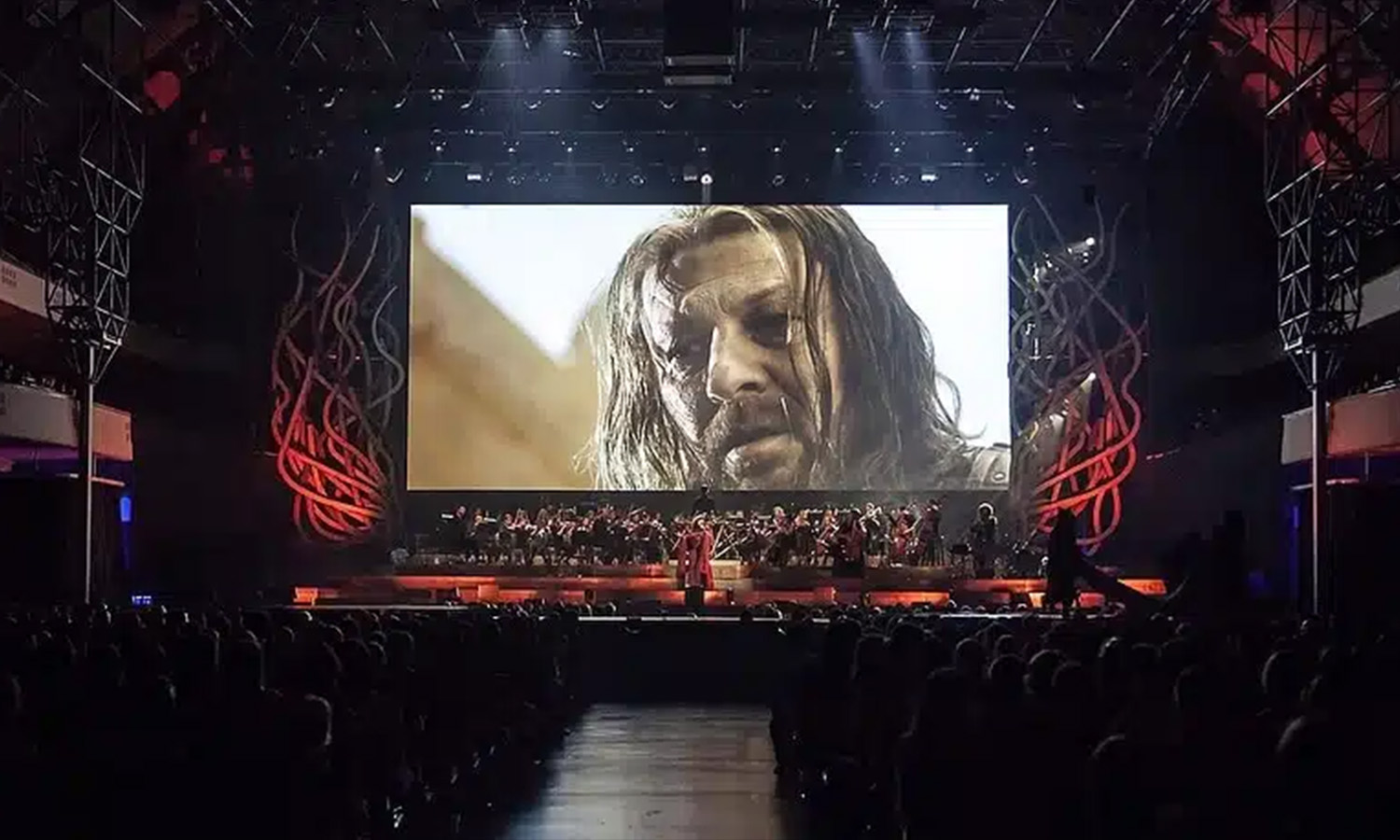 Komponist Ramin Djawadi dirigiert live ein großes Orchester auf der Bühne bei der Game of Thrones Concert Experience vor einer riesigen Videoleinwand.