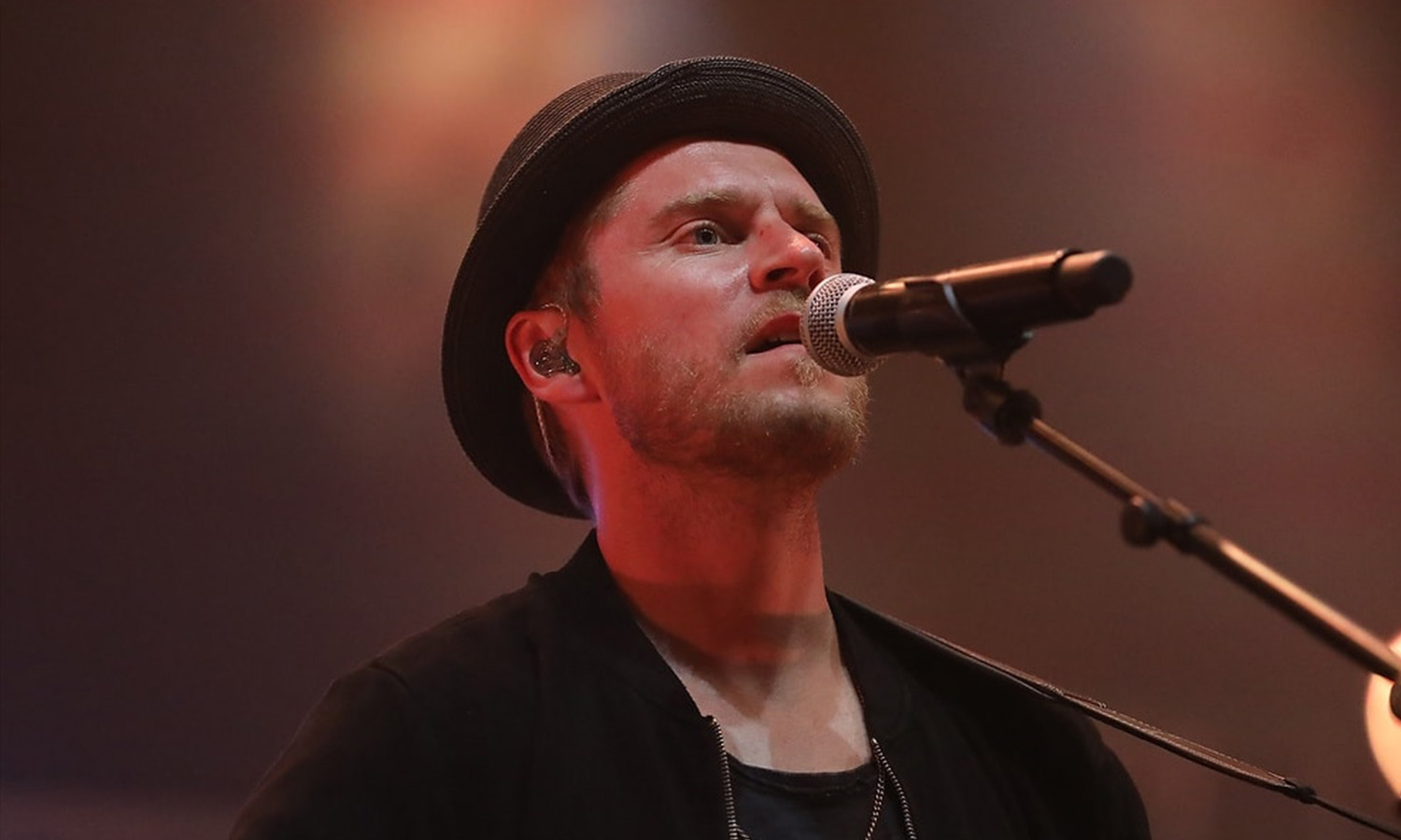 Sänger Johannes Oerding steht mit seinem typischen Hut und einer Gitarre live auf der Bühne beim Zeltfestival Rhein-Neckar in Mannheim vor Publikum.