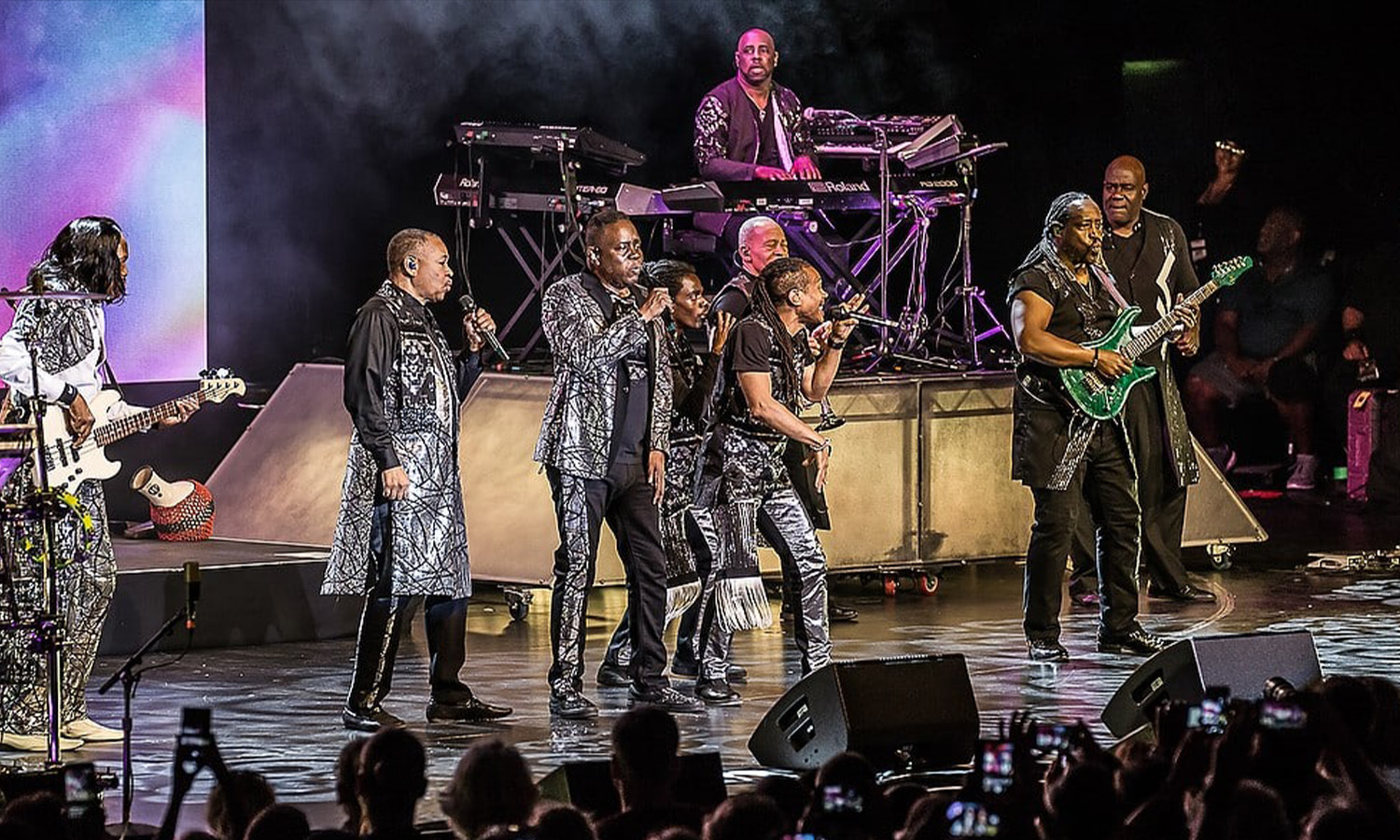 Philip Bailey und die Bandmitglieder von Earth, Wind & Fire stehen live auf der Bühne der Jahrhunderthalle Frankfurt vor tanzendem Publikum.