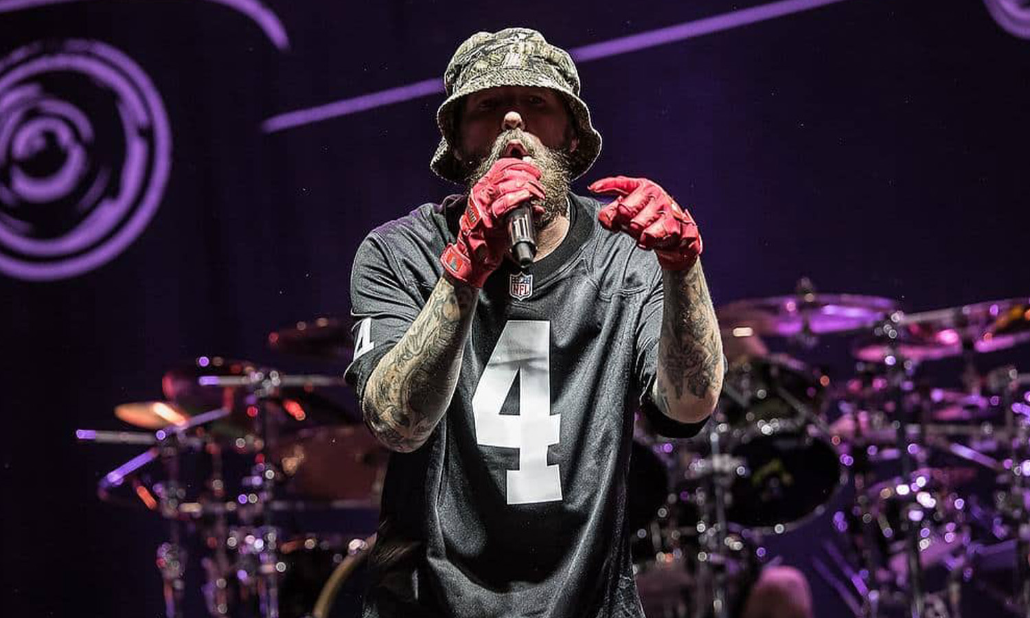 Fred Durst von Limp Bizkit steht gut gelaunt mit roter Kappe live auf der Bühne der Jahrhunderthalle Frankfurt vor feierndem Publikum.