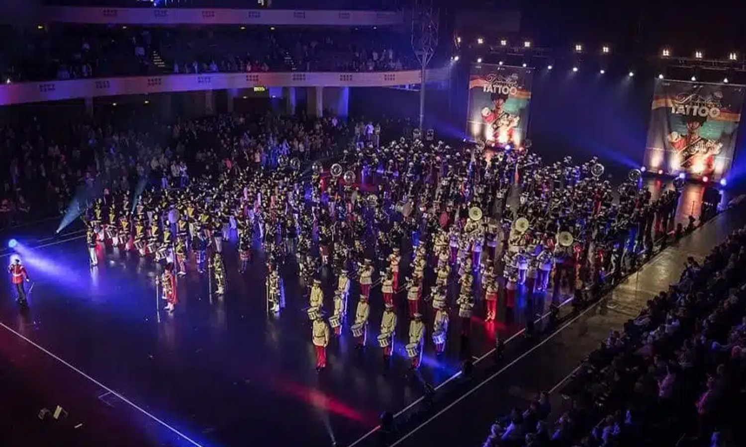 Zahlreiche Musiker einer Marching Band in bunten, traditionellen Uniformen stehen mit Instrumenten in der voll besetzten Frankfurter Festhalle.