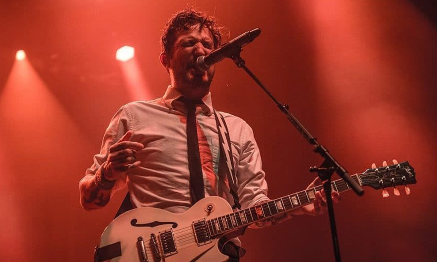 Singer-Songwriter Frank Turner steht mit einer Gitarre live auf der Bühne im Schlachthof Wiesbaden und singt leidenschaftlich in ein Mikrofon.