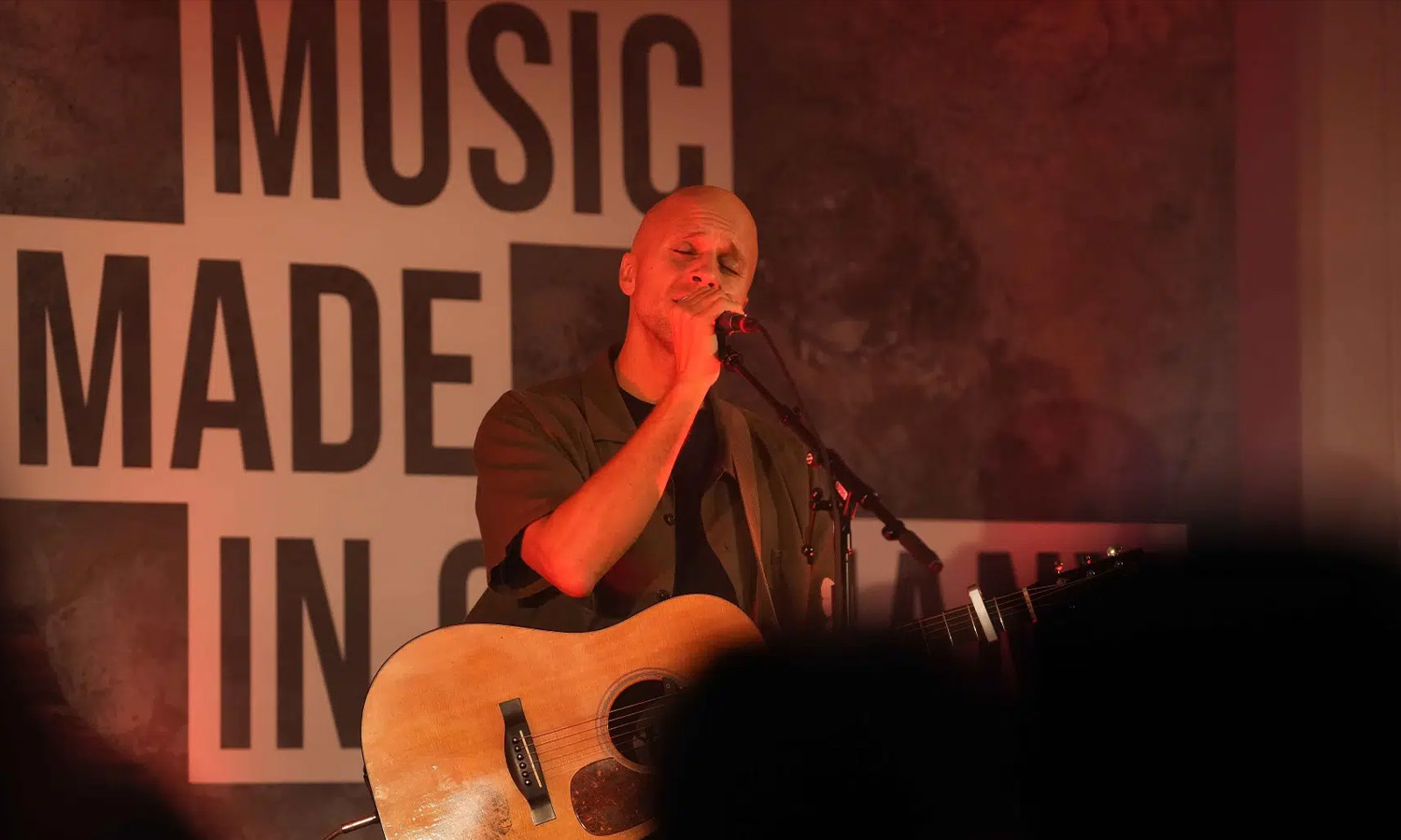 Milow singt leidenschaftlich und spielt Akustikgitarre beim intimen RPR1. Charity Konzert auf der Bühne.