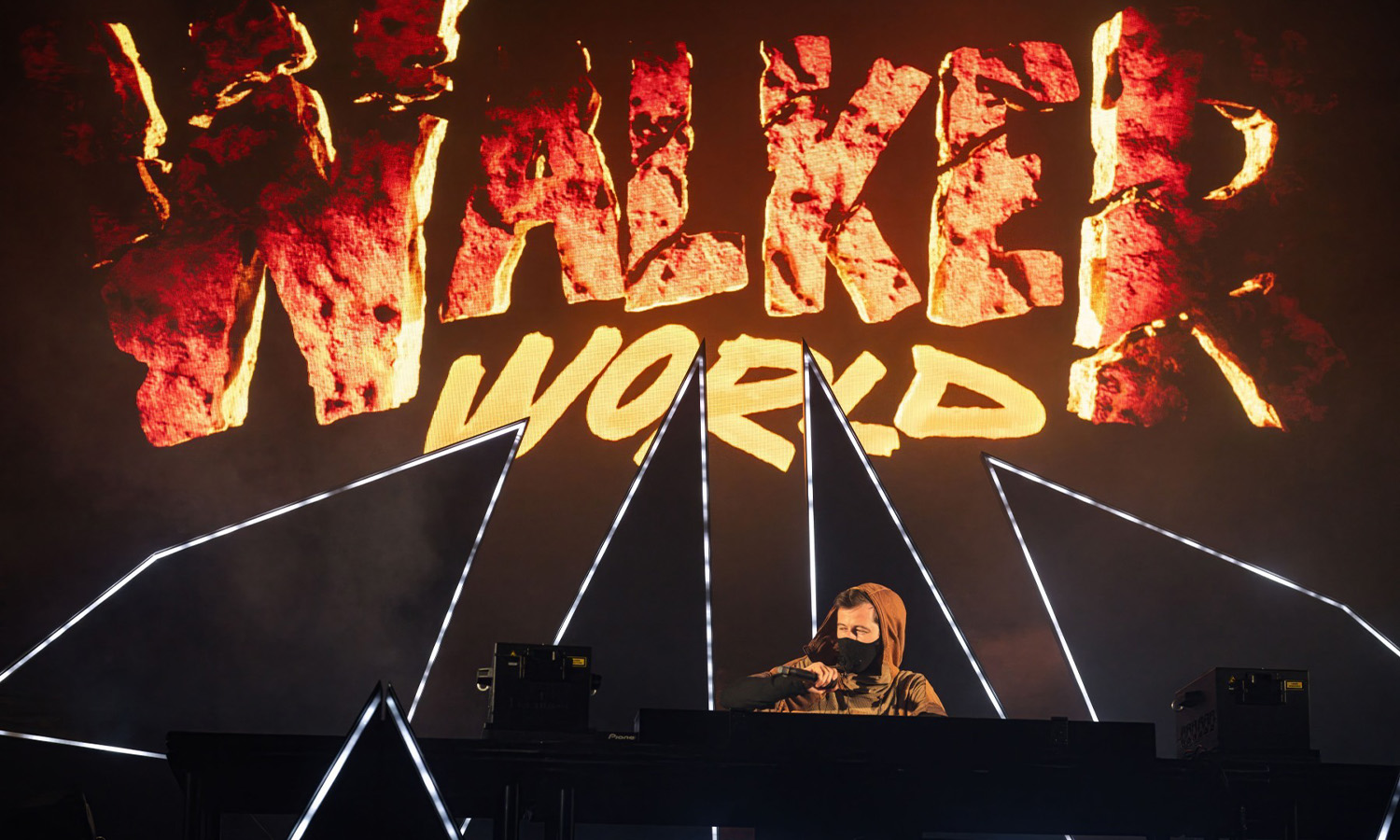 DJ Alan Walker steht mit Maske und Kapuzenpulli auf der Bühne der Jahrhunderthalle Frankfurt inmitten einer spektakulären Lichtshow.