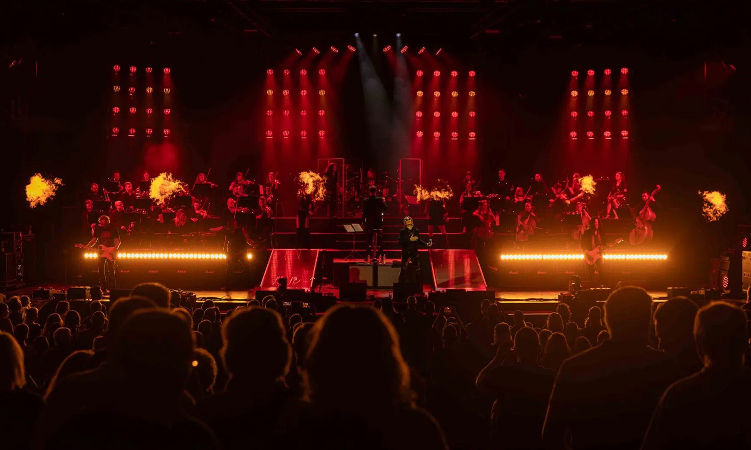 Rocklegenden stehen zusammen mit einem klassischen Orchester auf der stimmungsvoll beleuchteten Bühne der Jahrhunderthalle Frankfurt während der Rock Meets Classic Show 2025.