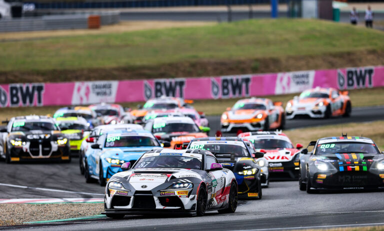 Ein Toyota GR Supra GT4 rast am 26.07.2026 bei strahlendem Sonnenschein über die Zielgerade der Rennstrecke in Oschersleben, umjubelt vom Team an der Boxenmauer.