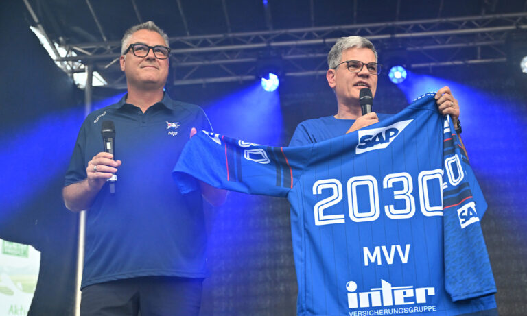 Spieler der Adler Mannheim präsentieren stolz das Trikot mit dem MVV-Schriftzug auf der Brust während einer offiziellen Pressekonferenz zur Vertragsverlängerung.